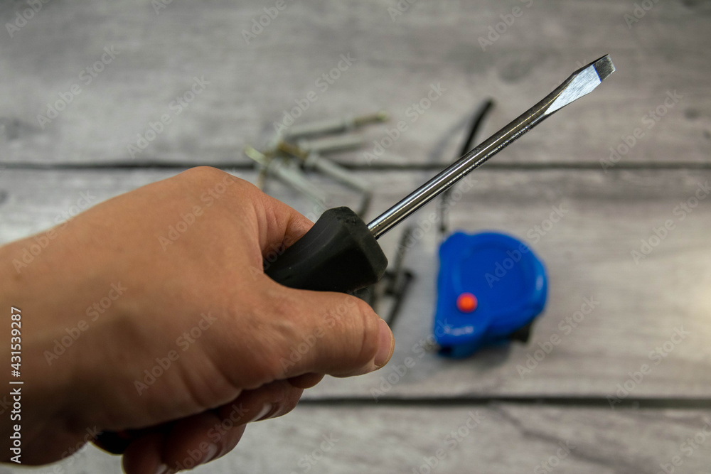 A black locksmith screwdriver in his hand on a gray background. A black locksmith screwdriver in his hand on a gray background.