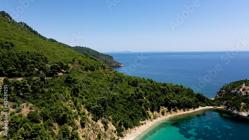 Fototapeta Naklejka Na Ścianę i Meble -  Aerial drone views over a rocky coastline, crystal clear Aegean sea waters, touristic beaches and lots of greenery in Skopelos island, Greece. A typical view of many similar Greek islands.