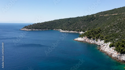 Aerial drone views over a rocky coastline, crystal clear Aegean sea waters, touristic beaches and lots of greenery in Skopelos island, Greece. A typical view of many similar Greek islands. © Krasi Kanchev