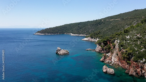 Aerial drone views over a rocky coastline, crystal clear Aegean sea waters, touristic beaches and lots of greenery in Skopelos island, Greece. A typical view of many similar Greek islands.