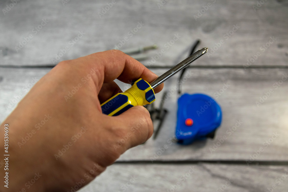 A black locksmith screwdriver in his hand on a gray background. A black locksmith screwdriver in his hand on a gray background.