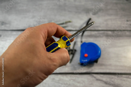 A black locksmith screwdriver in his hand on a gray background.