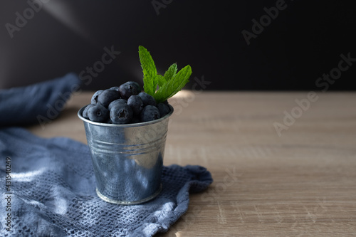 Fresh and sweet blueberry with mint in metal bucket on wooden table. Copy space.