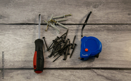 A black screwdriver, wood screws, and a tape measure.
