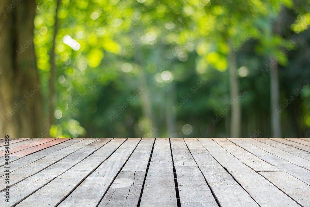 Wood floor with blurred trees of nature park background and summer season, product display montage Wood floor with blurred trees of nature park background and summer season, product display montage