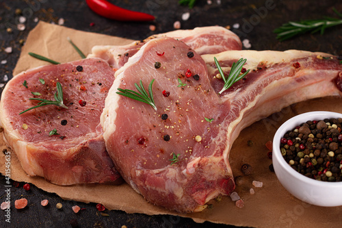 Raw meat for steak with ingredients for cooking on a dark background. Chop on the bone.