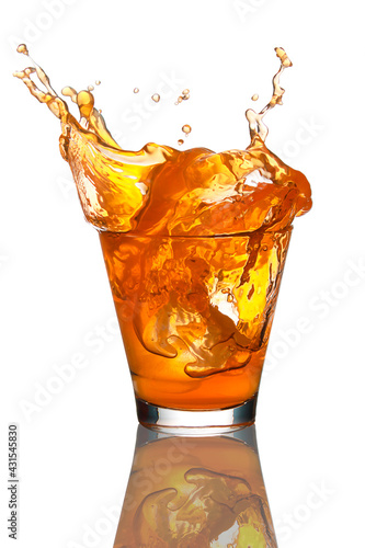 Ice falling in a glass of orange juice.