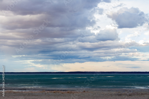 Brightsand lake Saskatchewan lake shore line in spring thaw with dark clouds and bright sky © Kara