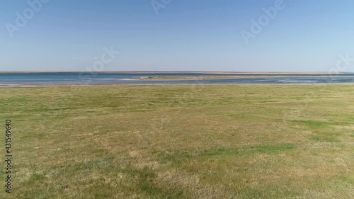 Flying over a green field, approaching the water