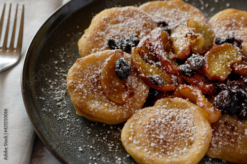 Apple pancake with caramelized apple slices and raisins, with powdered sugar