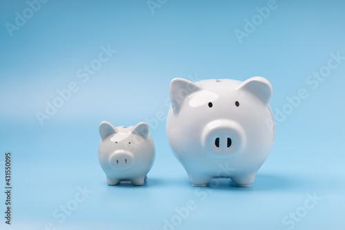 A family white piggy banks on blue background with copy space. Concept savings, investment, save money in the future.