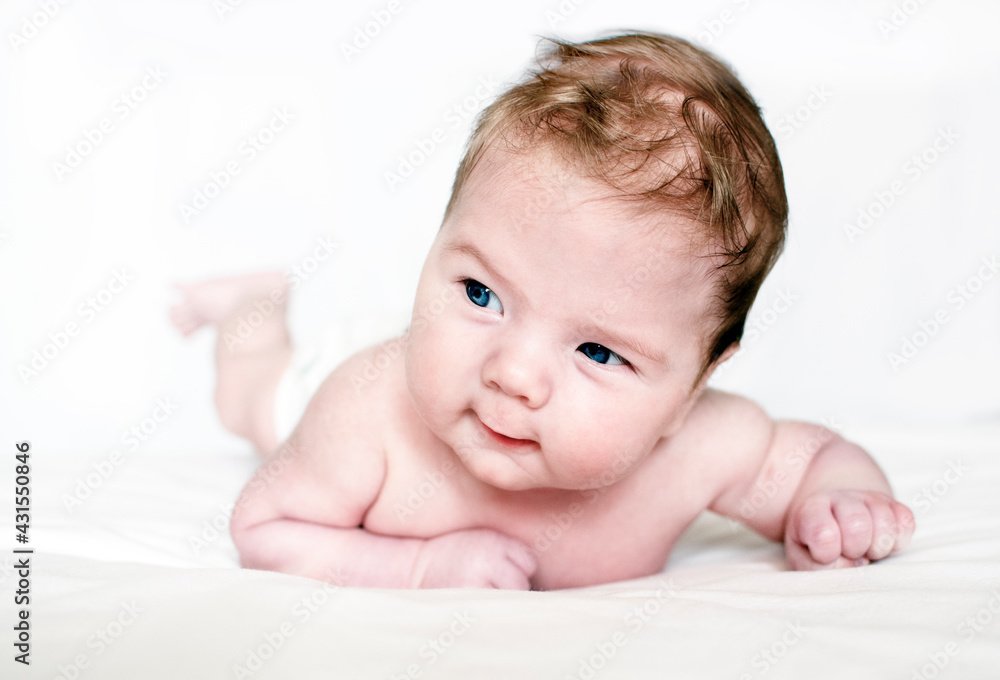 Bright portrait of a cute 3 months boy or girl. Newborn child has tummy time training Bright portrait of a cute 3 months boy or girl. Newborn child has tummy time training