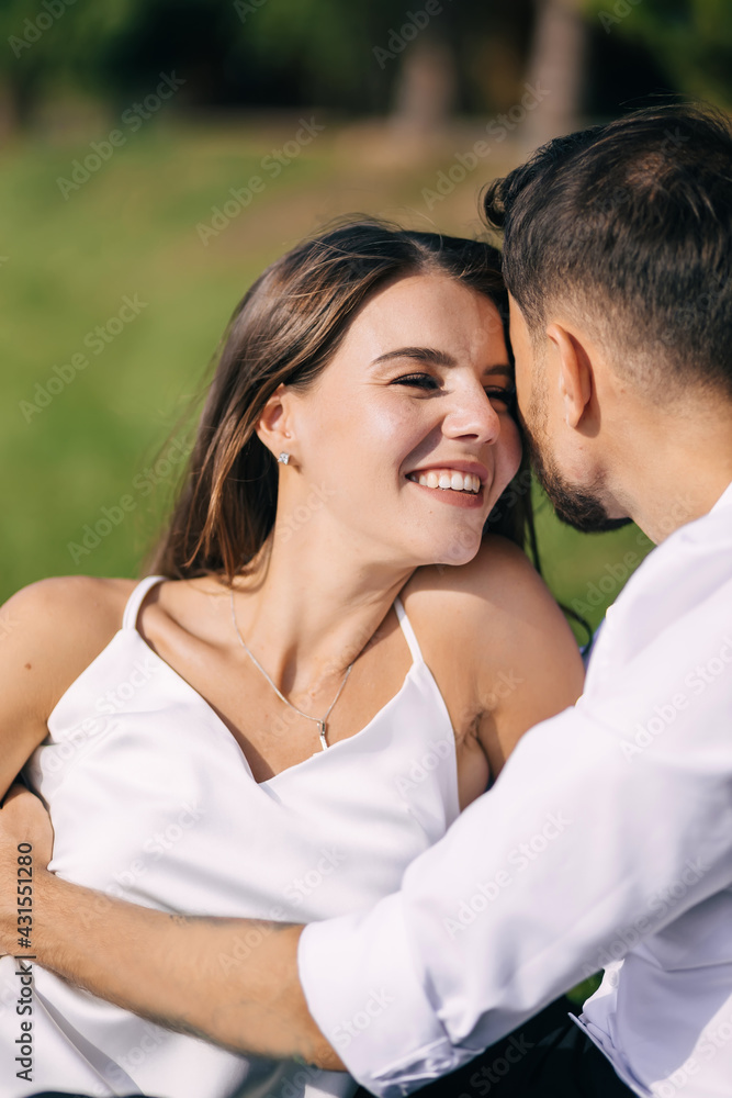 Happy young couple laying in grass on summer day. Man and wife newlyweds relaxing in sunny park after wedding. Happy young couple laying in grass on summer day. Man and wife newlyweds relaxing in sunny park after wedding.