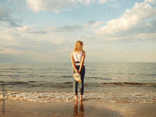 beautiful natural girl standing and admiring the sunset by the sea