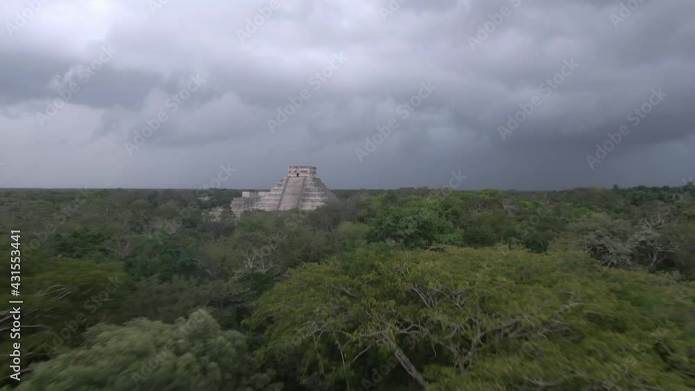 Aerial Shot Of Chichen Itza Amidst Trees Against Cloudy Sky, Drone Flying Forward Towards Famous Historic Landmark Aerial Shot Of Chichen Itza Amidst Trees Against Cloudy Sky, Drone Flying Forward Towards Famous Historic Landmark