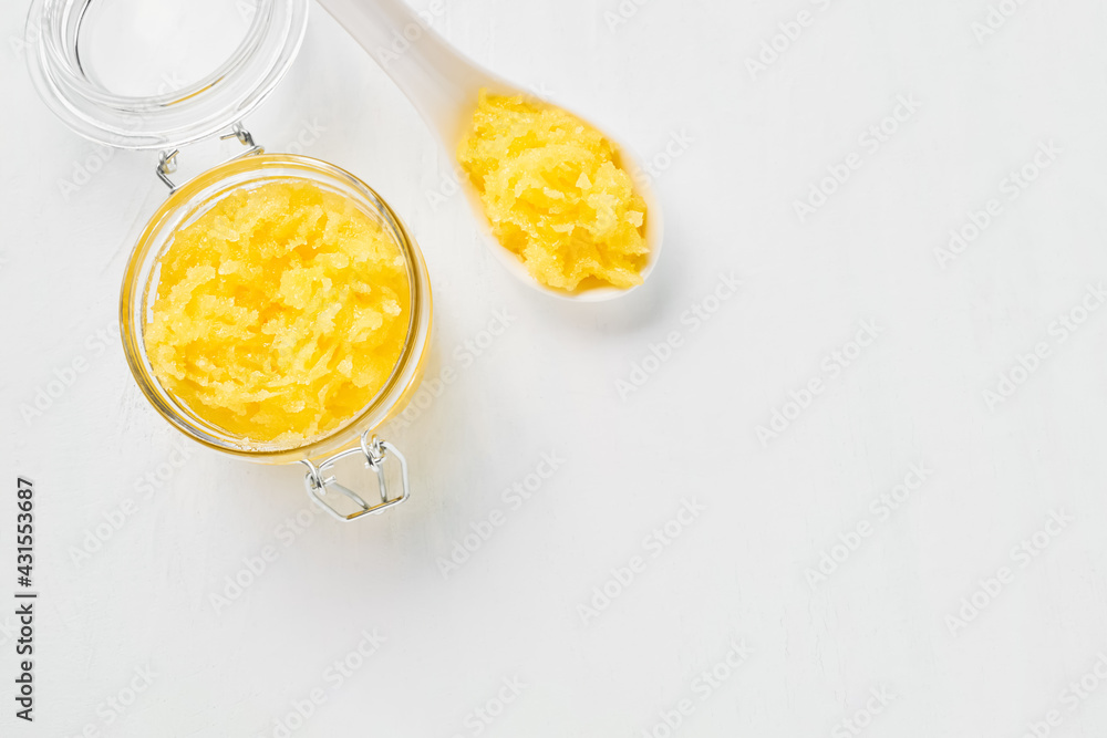 Homemade yellow body scrub in a glass jar on a white background. SPA concept Homemade yellow body scrub in a glass jar on a white background. SPA concept