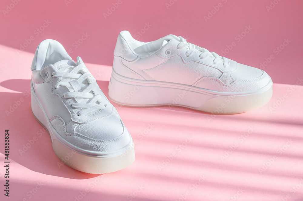 
White sneakers on a pink background.