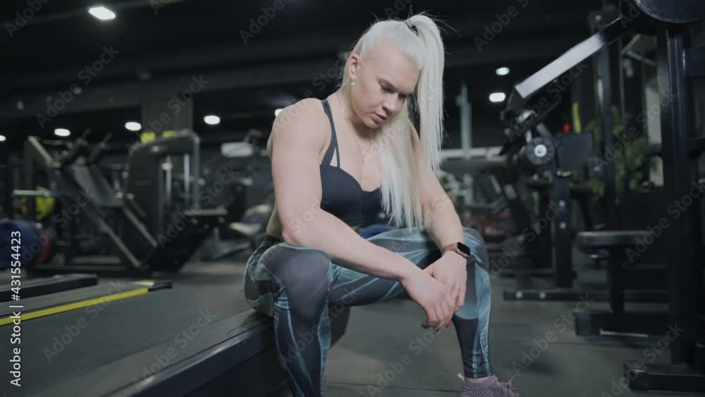 Young fitness girl is sitting and breathing heavily after a hard workout. Break between sets. Young fitness girl is sitting and breathing heavily after a hard workout. Break between sets.