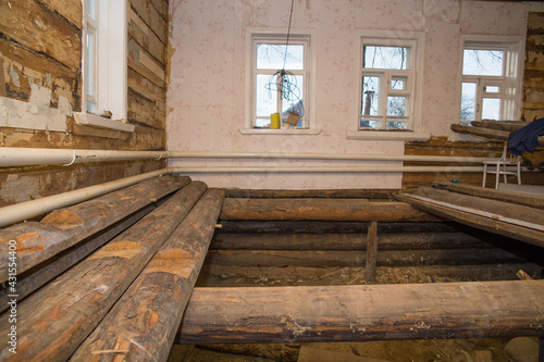 old village house with disassembled floor. Renovation in a village house. Selective focus on logs on the left side of the frame.
