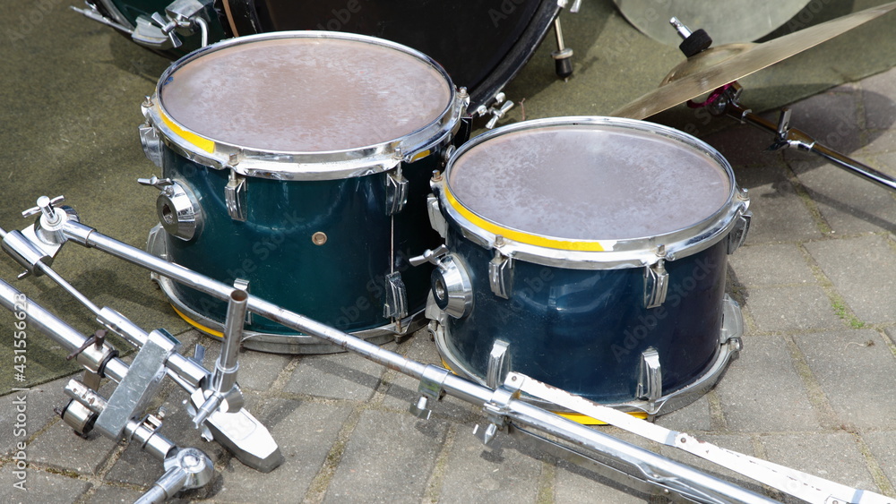 Obraz premium Disassembled old drums kit on stone pavement background, outdoor street music entertainment