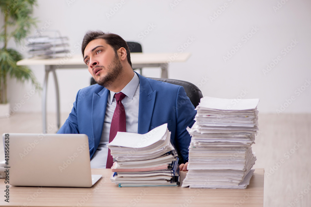 Young male employee and too much work in the office Young male employee and too much work in the office