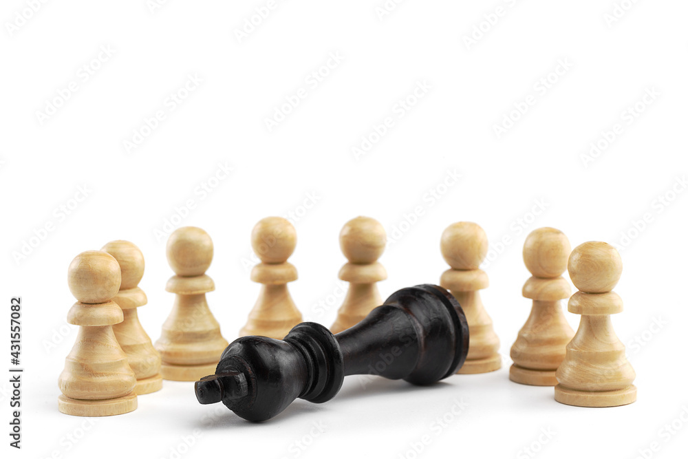 The black king lies in front of a row of white pawns on a white background. White wooden chess pieces, close-up.