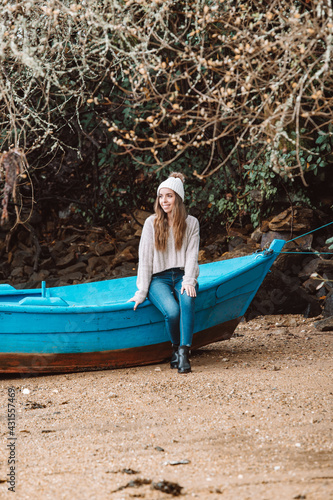 Smiling woman sitting on wooden boat on beach