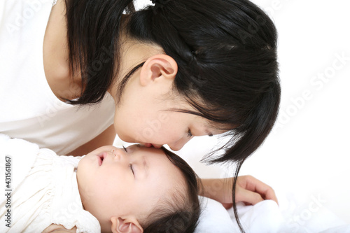 昼寝する赤ちゃんの額にキスするお母さん。母性、愛情イメージ