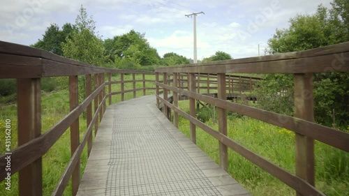 brown wooden bridge in the middle of nature on a path to cross a river. rural structure for ecological trail. country road with decorative wooden walkways.