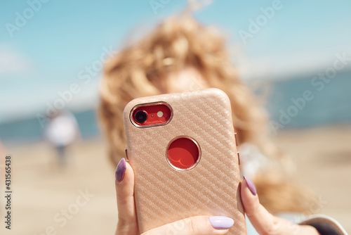girl taking a photo with a smartphone, selfie against the background of the sea on a sunny day,