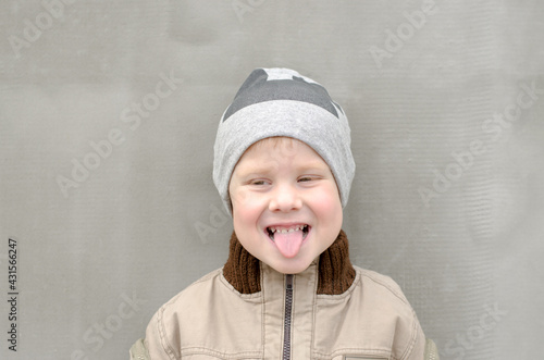 A 4-year-old boy shows his tongue. The child smiles and shows tongue
