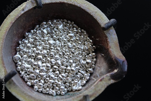 A ceramic crucible or melting pot with grains of sterling silver 925 for jewelry making after hand smelting in a workshop. One of the two major precious metals on the market.