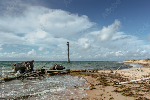 Sunny summer day by Baltic Sea.Wandelust Travel background.Power of water energy passing.Amazing view of cold sea with old lighthouse, waves and pebble sandy beach.Coastline of Estonia photo