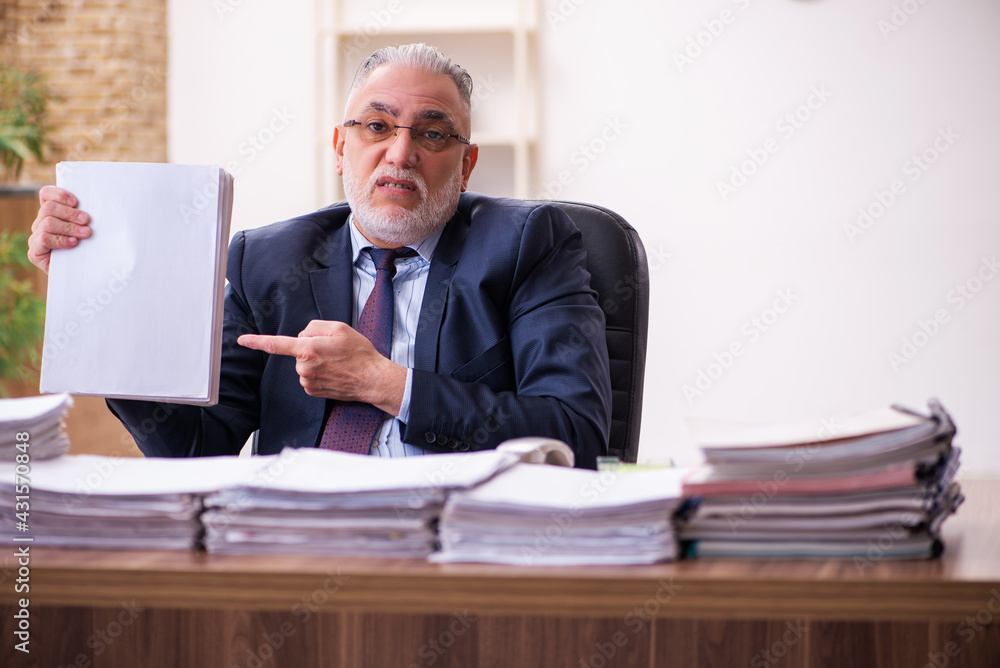 Old businessman employee unhappy with excessive work in the office Old businessman employee unhappy with excessive work in the office