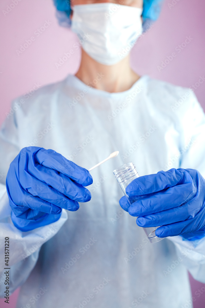 Doctor or nurse in protective mask holds test tube and cotton swab in his hands for a test to check for bacteria and viruses. Coronavirus test. Close-up. Doctor or nurse in protective mask holds test tube and cotton swab in his hands for a test to check for bacteria and viruses. Coronavirus test. Close-up.