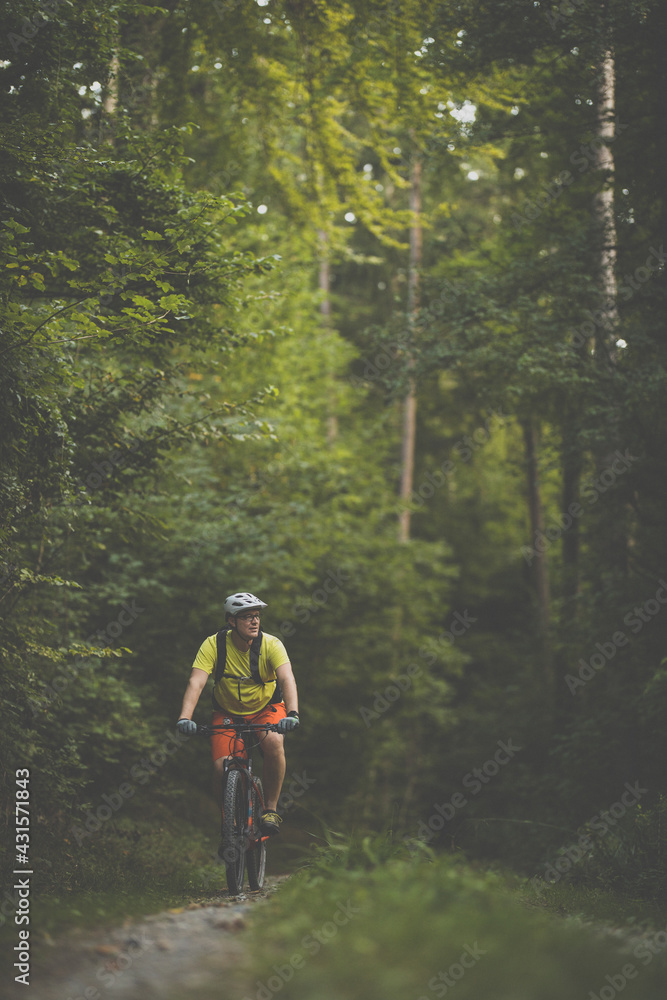 Young man with his mountain bike going for a ride past the city limits in a lovely forest, getting the daily cardio dose Young man with his mountain bike going for a ride past the city limits in a lovely forest, getting the daily cardio dose