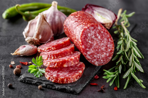 Traditional smoked salami sausage with spices.Salami sausage slices on a black chopping Board. Dark background. photo