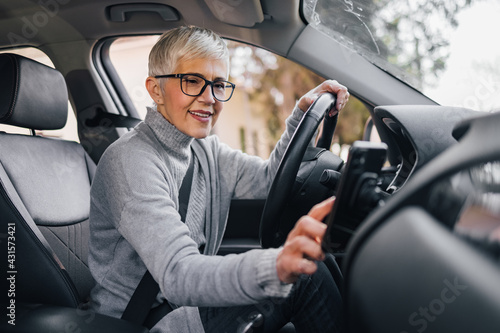 Senior female driver setting navigation on smart phone before a drive.