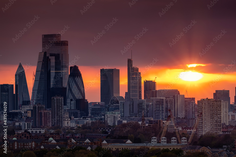 The skyline of the City of London with the modern office skyscrapers shining in the red sunset light