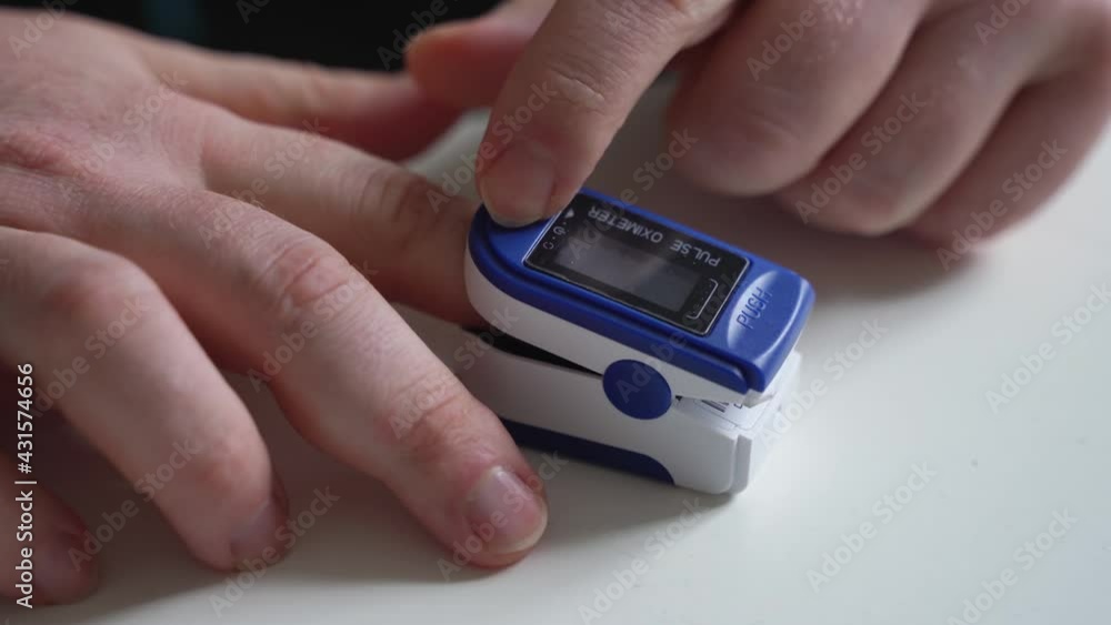 Unrecognised man's hands at home checking blood oxygen level with pulse