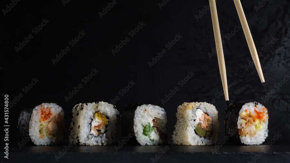 sushi set in a row on a stone board with chopsticks on a dark plaster background. artistic moody food photo with copy space sushi set in a row on a stone board with chopsticks on a dark plaster background. artistic moody food photo with copy space