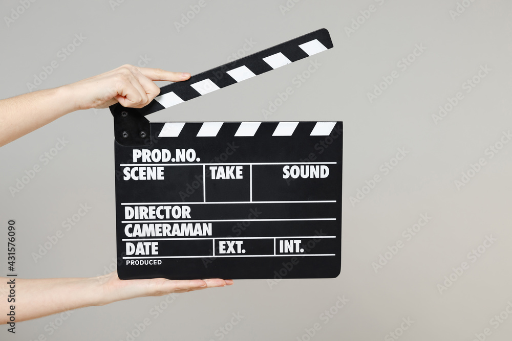 Obraz premium Close up cropped female holding in hand classic director clear empty black film making clapperboard isolated on grey background. Cinematography production concept. Copy space for advertising mock up.