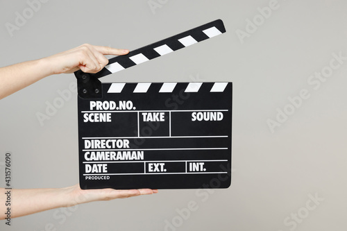 Close up cropped female holding in hand classic director clear empty black film making clapperboard isolated on grey background. Cinematography production concept. Copy space for advertising mock up.