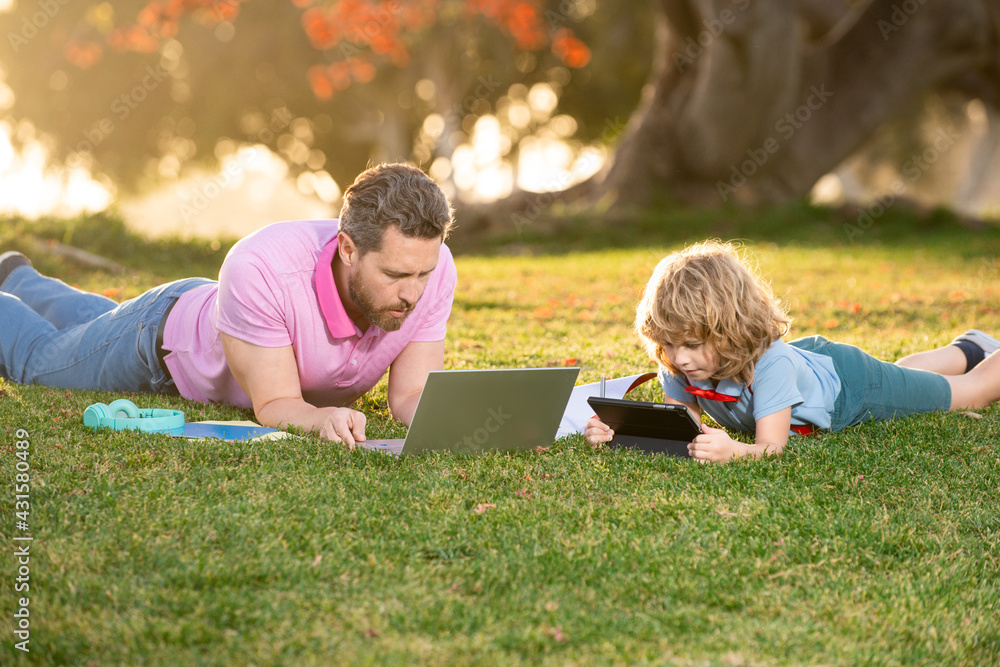 Outdoor learning. Blogging. Happy father using laptop relax with schooler son holding laptop. Childhood and parenthood kids concept. Video lesson. Outdoor learning. Blogging. Happy father using laptop relax with schooler son holding laptop. Childhood and parenthood kids concept. Video lesson.