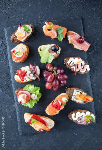 A set of classic Spanish and Italian sandwiches - tapas and bruschetta - a traditional dish of Mediterranean cuisine. Shrimps, octopus, salmon, cheese, herbs, fruits were used in the preparation - top