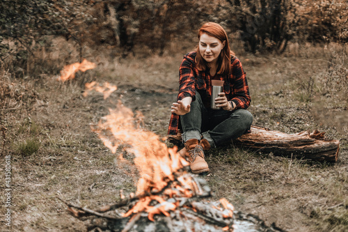 Woman camping in the forest and relaxing near campfire after a very hard day. Concept of trekking, adventure and seasonal vacation.
