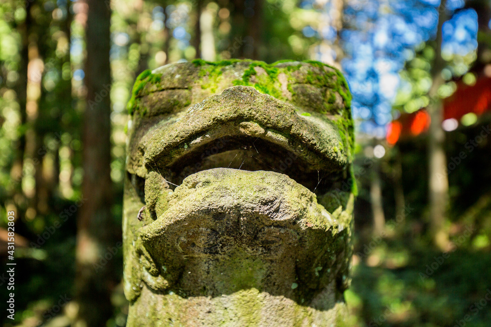 Stone Lion dog statue covered in green moss in a Japanese shrine within a forest in Takayama, Japan. Stone Lion dog statue covered in green moss in a Japanese shrine within a forest in Takayama, Japan.