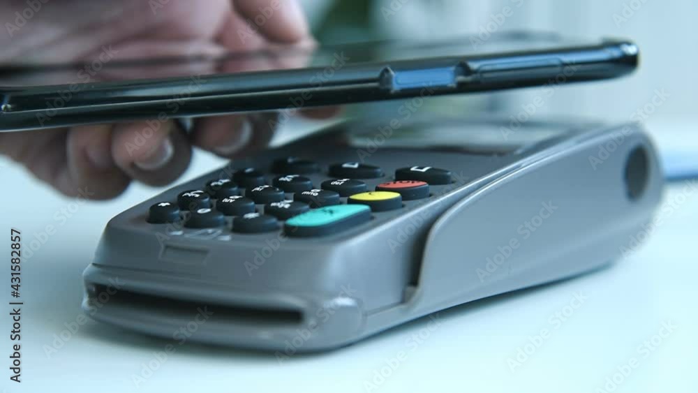 Hand Using Smart Phone For Payment With Nfc Techology. Mobile Payment And Online Shopping Concept. Slow Motion Effect. Close Up Hand Using Smart Phone For Payment With Nfc Techology. Mobile Payment And Online Shopping Concept. Slow Motion Effect. Close Up