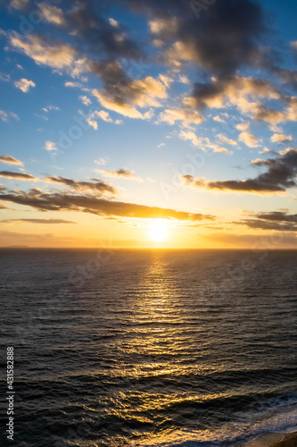 A dramatic sunset over the ocean with colorful skies and color being reflected in the waves below.