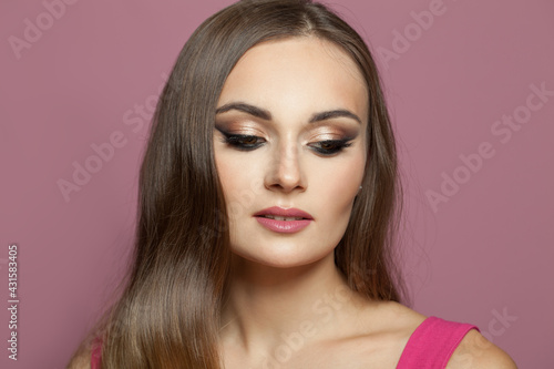 Beautiful woman face with makeup on pink background